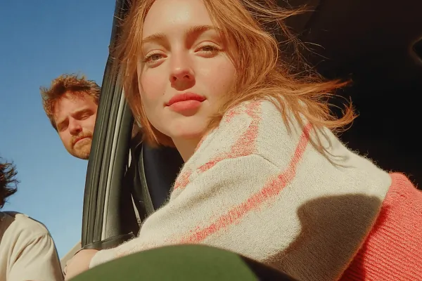 Two people in a car on a sunlit road
