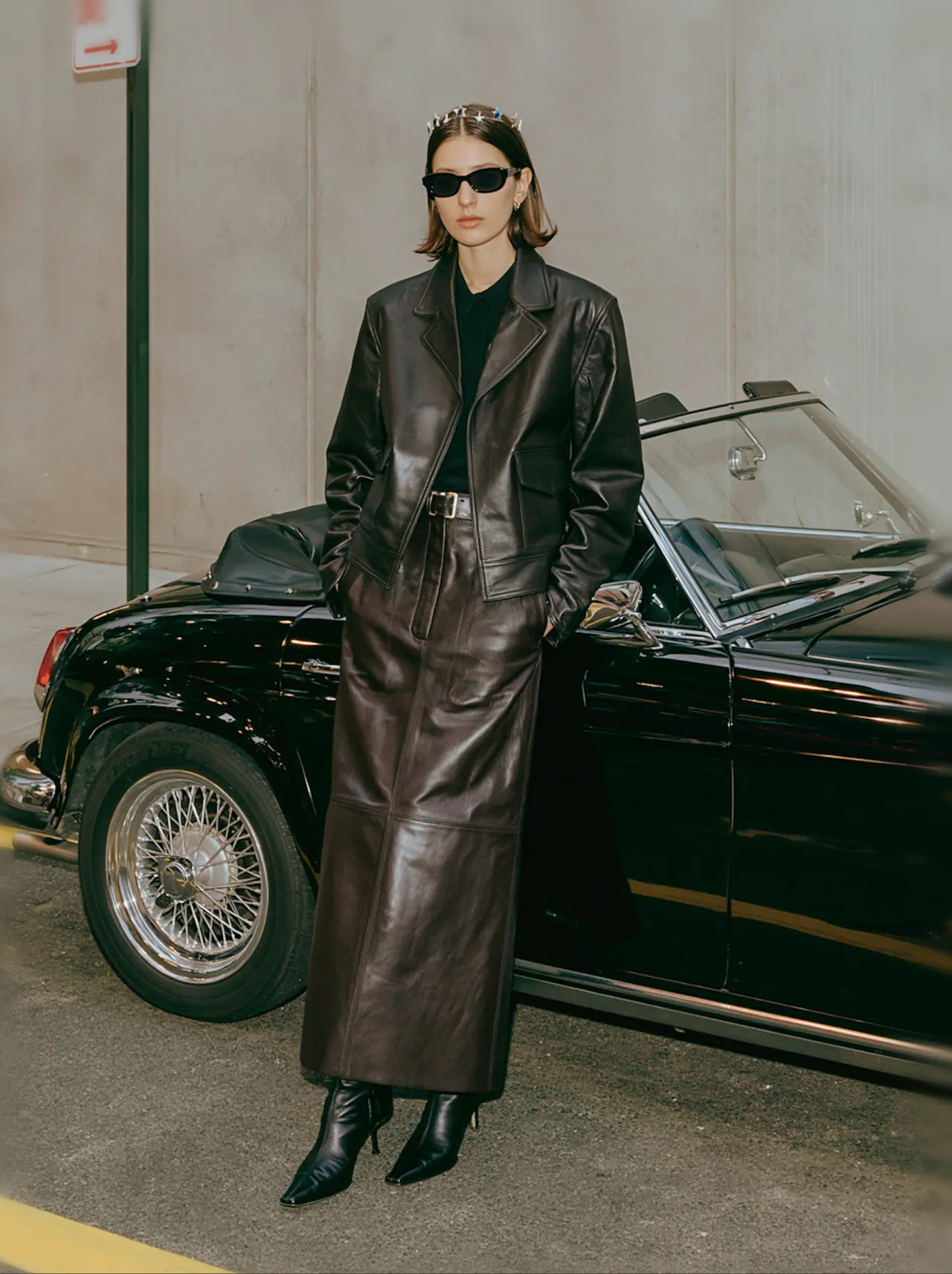 Person in leather standing beside a vintage convertible